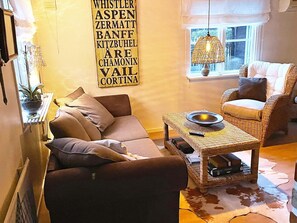 A cozy living room with a sofa, a wicker coffee table, and a wicker chair.