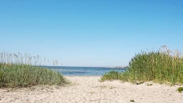 A sandy beach with clear blue sky and calm sea.