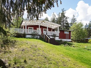 A red cabin with a white porch and stairs leading to a door. - 5 Person Holiday Home in Strangnas (Strängnäs)