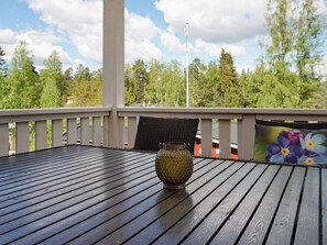 Enjoy a serene view of the surrounding forest from this deck, which features a table and decorative vase.