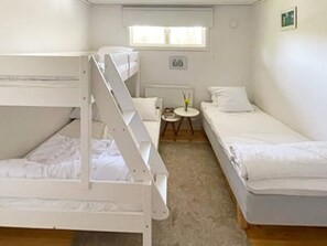 Cozy room with a bunk bed and single bed, a small table, and a window.