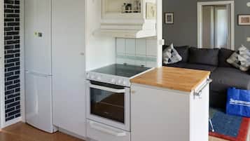 Una cocina compacta con horno integrado, microondas y una pequeña encimera.