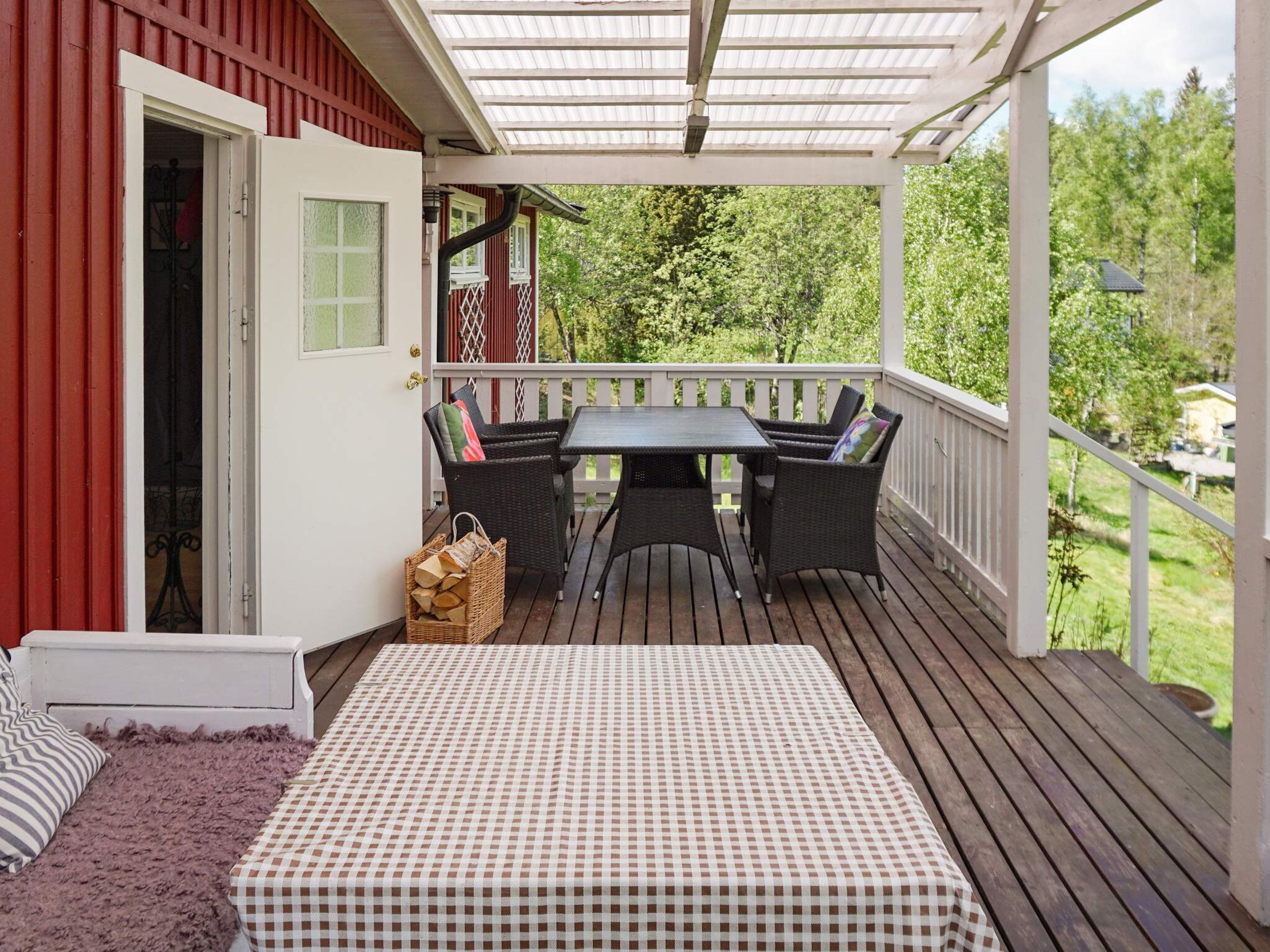 A covered outdoor seating area with a table and chairs, a wicker sofa, and a checkered tablecloth.