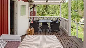A covered outdoor seating area with a table and chairs, a wicker sofa, and a checkered tablecloth.