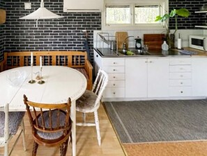 A kitchen with a round table, chairs, a white cabinet, a microwave, and a window. - 5 Person Holiday Home in Strangnas (Strängnäs)