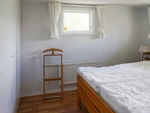 A bedroom with a wooden bed, a window with curtains, a radiator, and a wooden ladder. - 5 Person Holiday Home in Strangnas (Strängnäs)