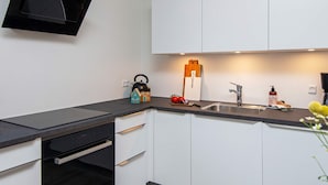A modern kitchen with white cabinets, a black countertop, and a kettle. - 5 Star Holiday Home in Ansager (Ansager)