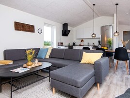 Una sala de estar moderna con un sofá seccional gris, una mesa de centro y un comedor con sillas y una mesa.