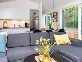 Una cocina moderna con refrigerador empotrado, un comedor con mesa y sillas, y un amplio ventanal con vistas al exterior.