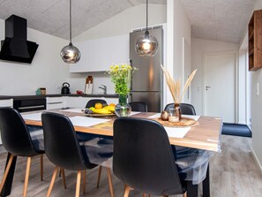 Eine moderne Küche mit Essbereich, ausgestattet mit einem Holztisch, schwarzen Stühlen und einer Blumenvase.