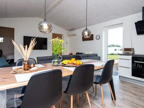 Um espaço moderno de estar, com área de refeições, cozinha e espaço para sentar.