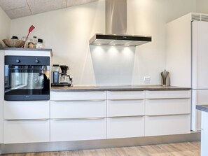 A modern kitchen with a built-in oven, a coffee machine, and a stainless steel range hood.