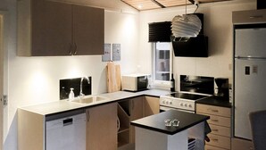 A compact kitchen with a dishwasher, stove, microwave, and refrigerator.