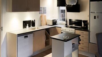 A compact kitchen with a dishwasher, stove, microwave, and refrigerator.
