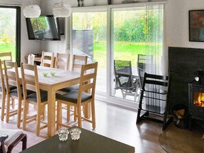 A dining area with a table and chairs, a fireplace, and a television mounted on the wall. - 4 Star Holiday Home in Sydals (Sydals)