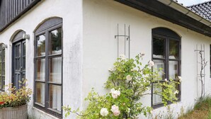 A white building with three arched windows and a rose bush in front. - 6 Person Holiday Home in Laeso (Læsø)