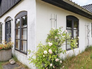 En vit byggnad med tre bågformade fönster och en rosenbuske framför.