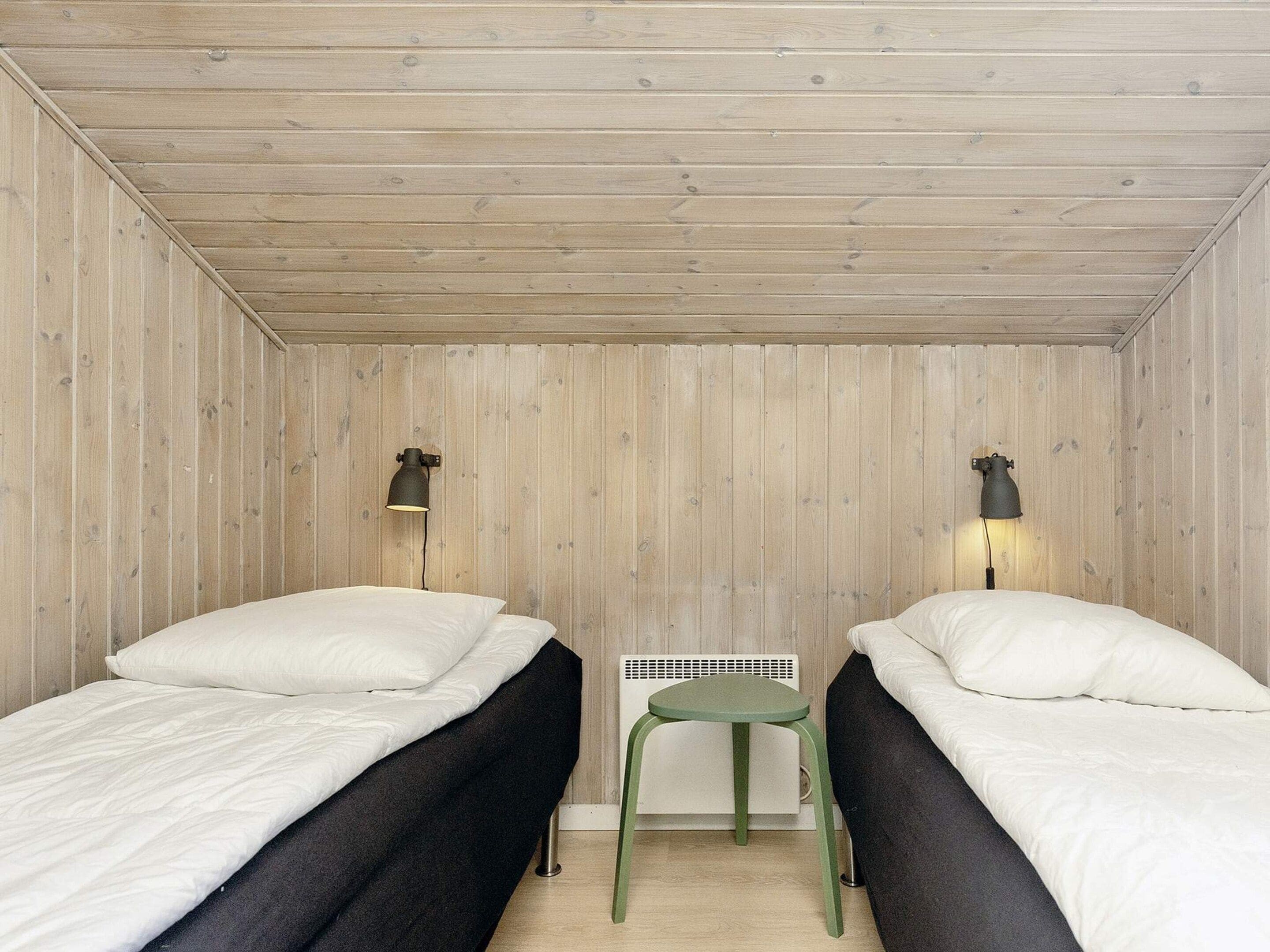 Ein kleines, gemütliches Zimmer mit zwei Einzelbetten, einem kleinen Tisch und zwei Wandlampen.