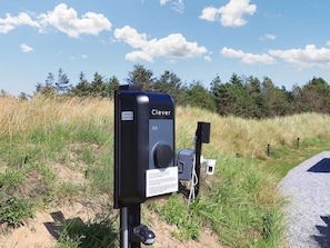 A black outdoor device labeled 'Clever' with a dial, a small box, and a sensor on a post in a grassy area. - 14 Person Holiday Home in Blokhus (Blokhus)