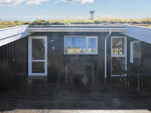 A covered outdoor area with a table and chairs, a window, and a view of the landscape. - 14 Person Holiday Home in Blokhus (Blokhus)