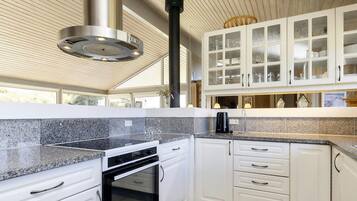 A modern kitchen with white cabinetry, granite countertops, and a stainless steel range hood.