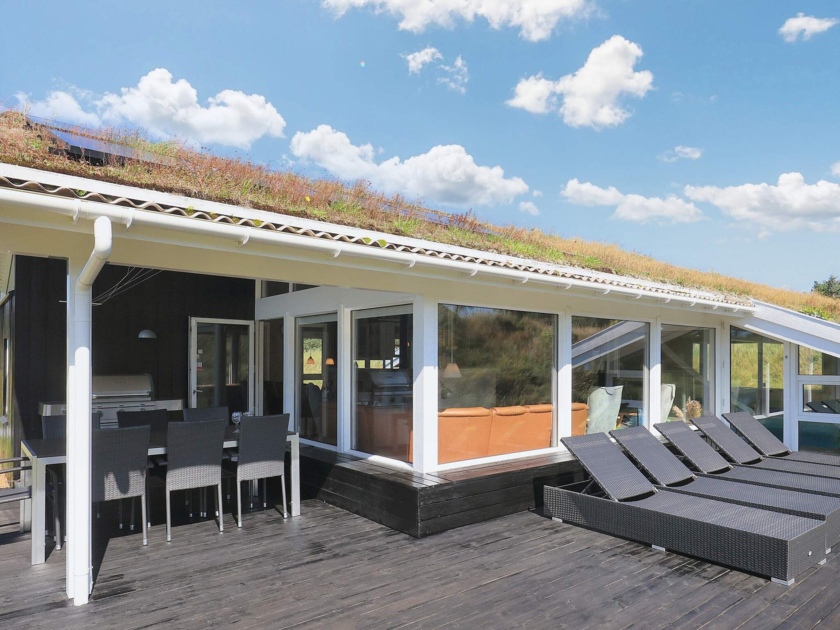 A covered outdoor area with a grill, seating, and a view of the sky.