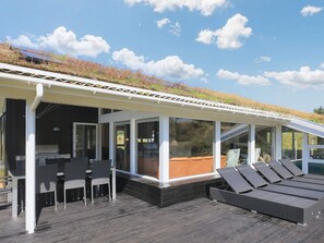 A covered outdoor area with a grill, seating, and a view of the sky.