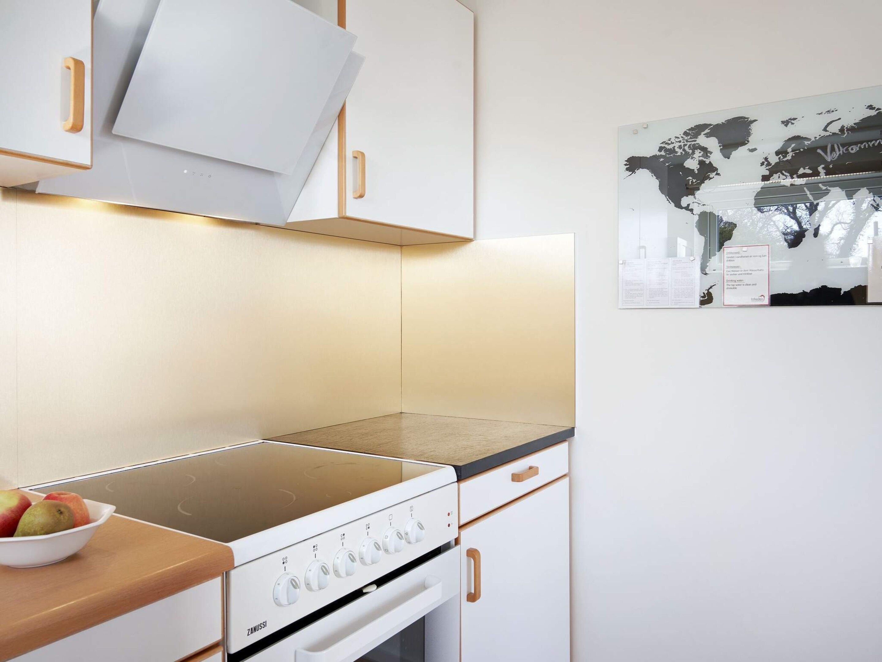 Una cocina con estufa, armarios y un mapa mundial en la pared.