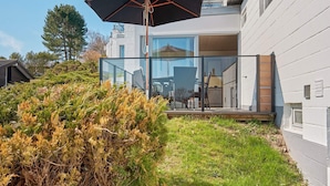 A modern house with a glass balcony, a wooden deck, and a large umbrella. - 4 Star Holiday Home in Allinge (Allinge)