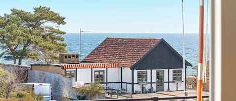 A coastal building with a tiled roof, a balcony, and a view of the sea.