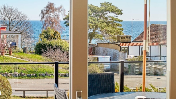 Un balcón con vistas al mar, una silla y una mesa.