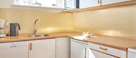 Una cucina compatta con lavastoviglie, forno a microonde e lavello.