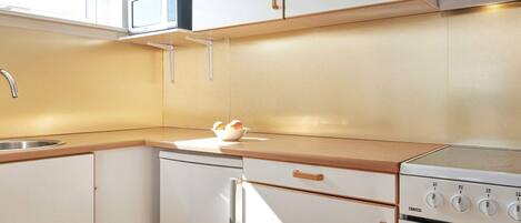A modern kitchen with white cabinets, a stainless steel sink, a microwave, and a Zanussi oven.