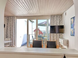 Habitación con techo de madera, televisor montado en la pared y vistas al exterior.