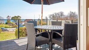 A balcony with a table and chairs, an umbrella, and a view of the sea. - 4 Star Holiday Home in Allinge (Allinge)