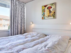 A bedroom with a bed, curtains, a wall-mounted light, and a painting. - 4 Star Holiday Home in Allinge (Allinge)