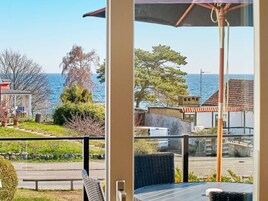 Un balcón con vista al mar, una silla y una mesa.