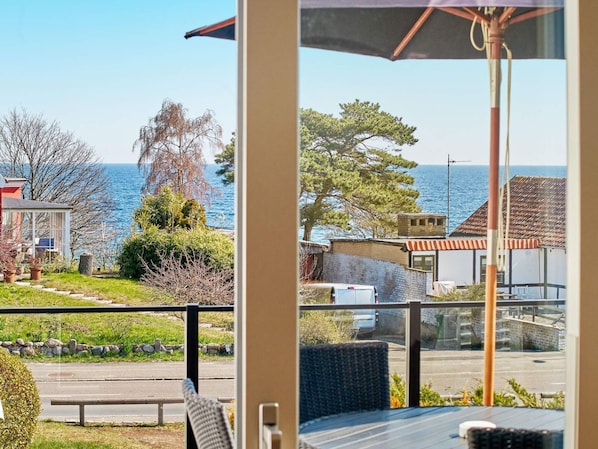 A balcony with a view of the sea, a chair, and a table.