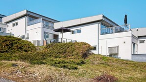 A modern multi-story building with large windows, a balcony, and a clear sky. - 4 Star Holiday Home in Allinge (Allinge)