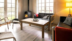A cozy living room with a wood-burning stove, a sofa, a table, and a chair. - 10 Person Holiday Home in Vaeggerlose-by Traum (Vaeggerlose)
