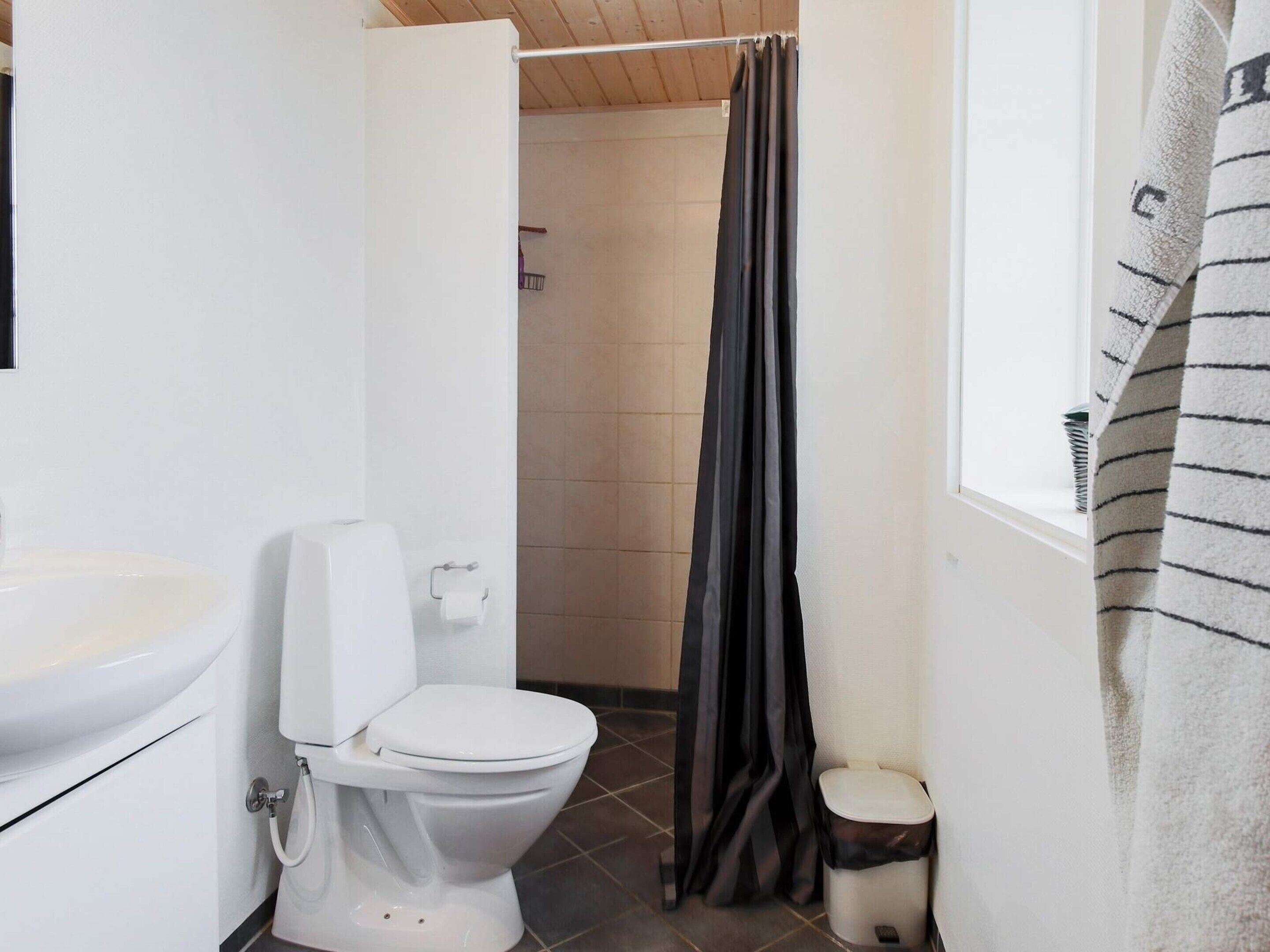 Une salle de bain équipée de toilettes, d’un lavabo et d’un rideau de douche.