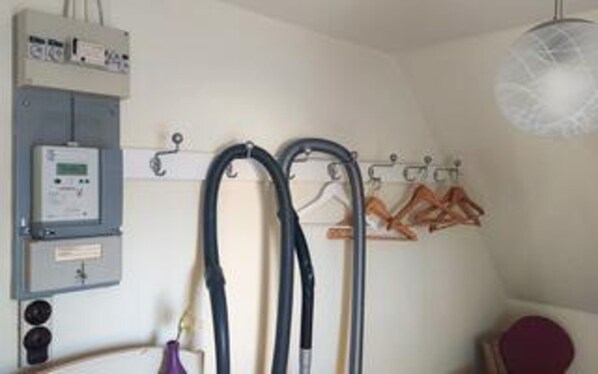 A medical room with a control panel, a wall-mounted heater, and a rack of hangers.