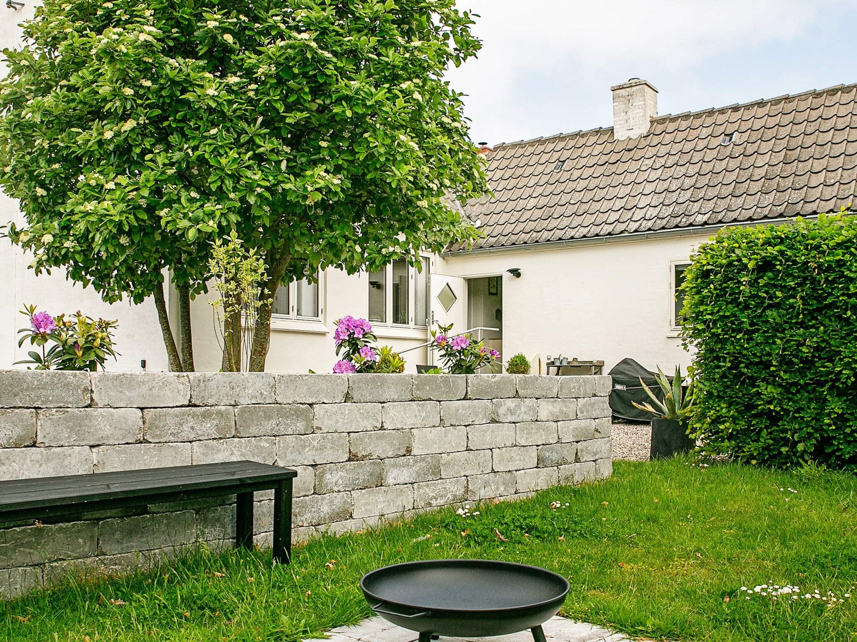 Een terras met een stenen muur, een ronde tafel en een bank.