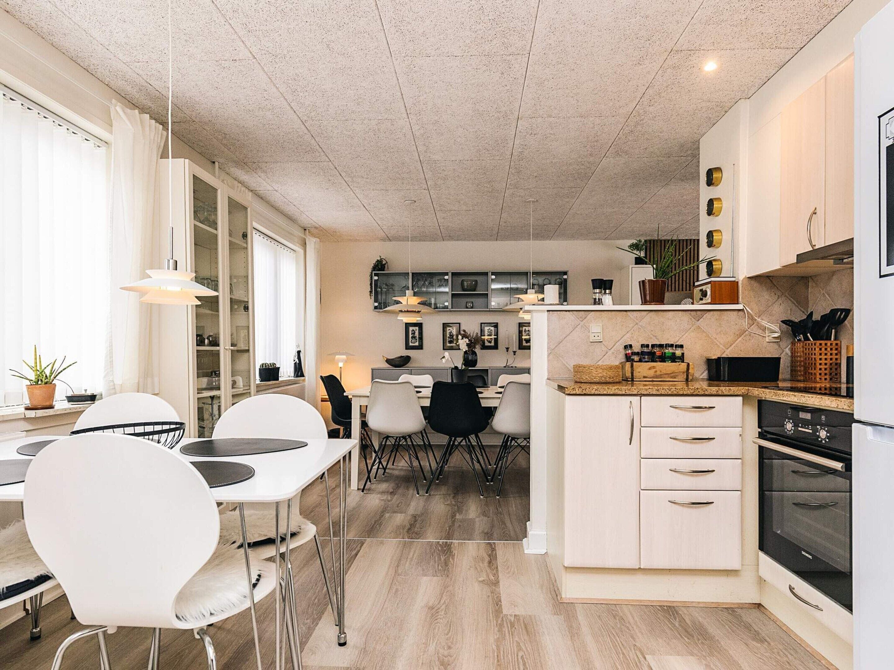 Una cocina moderna con comedor, suelo de madera y vista al salón.