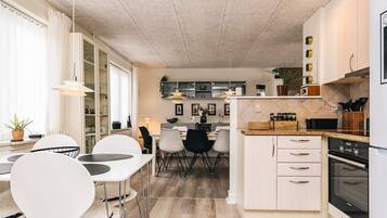 Una cocina moderna con comedor, suelo de madera y vista al salón.