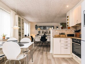 Une cuisine moderne avec un coin repas, un plancher en bois et une vue sur le salon.