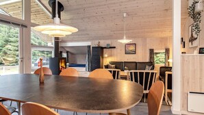 Um interior moderno com uma grande mesa de jantar, cadeiras de madeira e uma lareira.