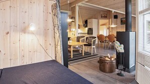 Interior acolhedor de uma cabana com área de refeições, cozinha e lareira a lenha.