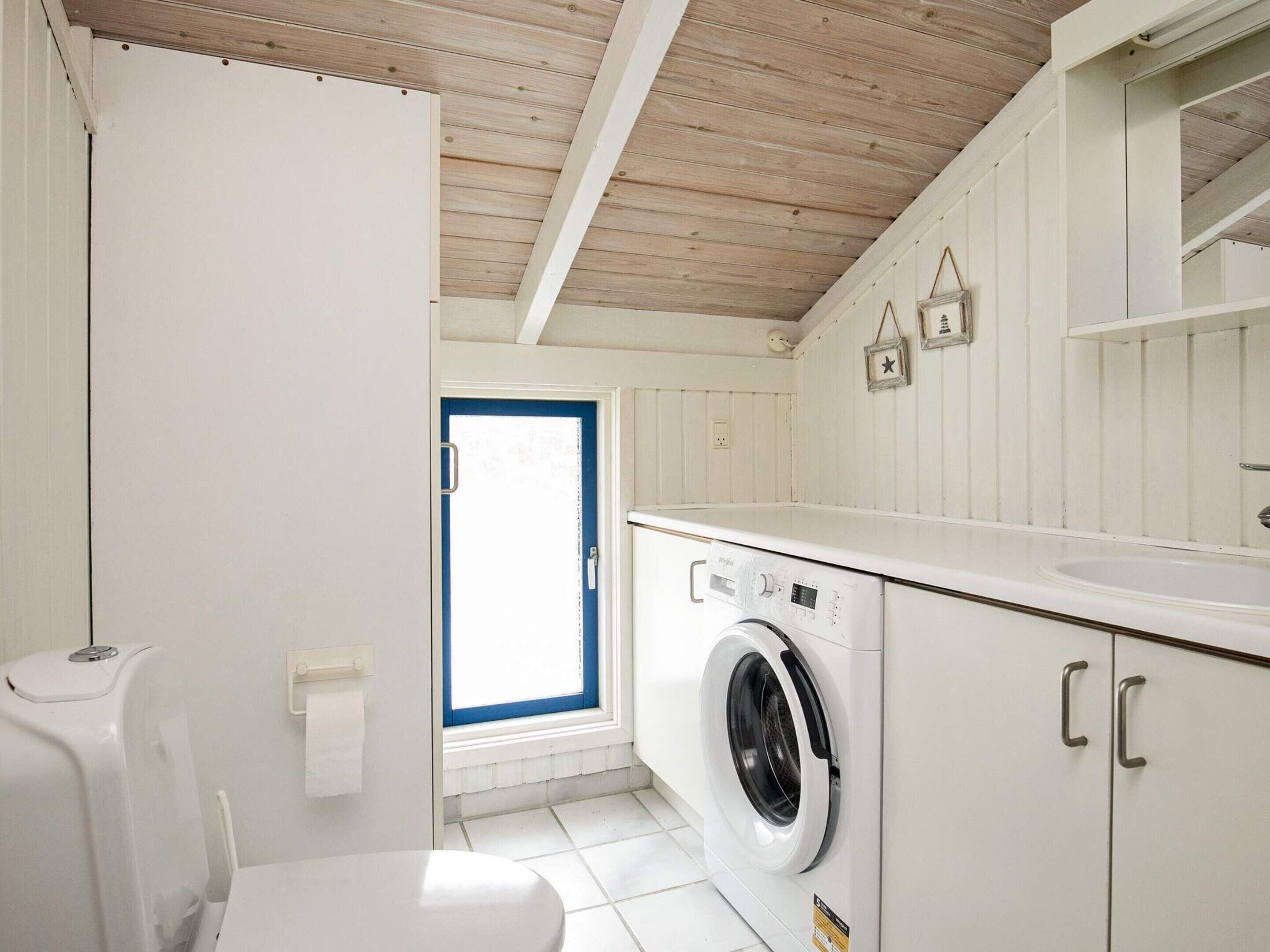 A laundry room with a washing machine, a toilet, and a sink.