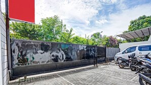 A paved courtyard with a metal fence, a white van, and several motorcycles parked. - OYO Flagship  90789 Genteng Residence (Surabaya)